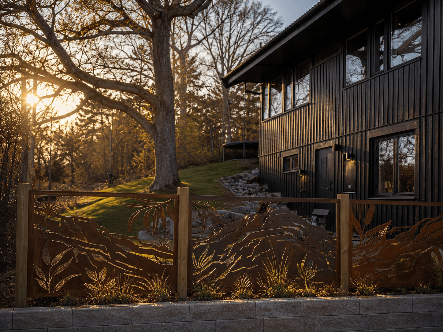 Laser-cut Corten steel bush fence panel with Australian bush motif, uplit at dusk, Stockholm
